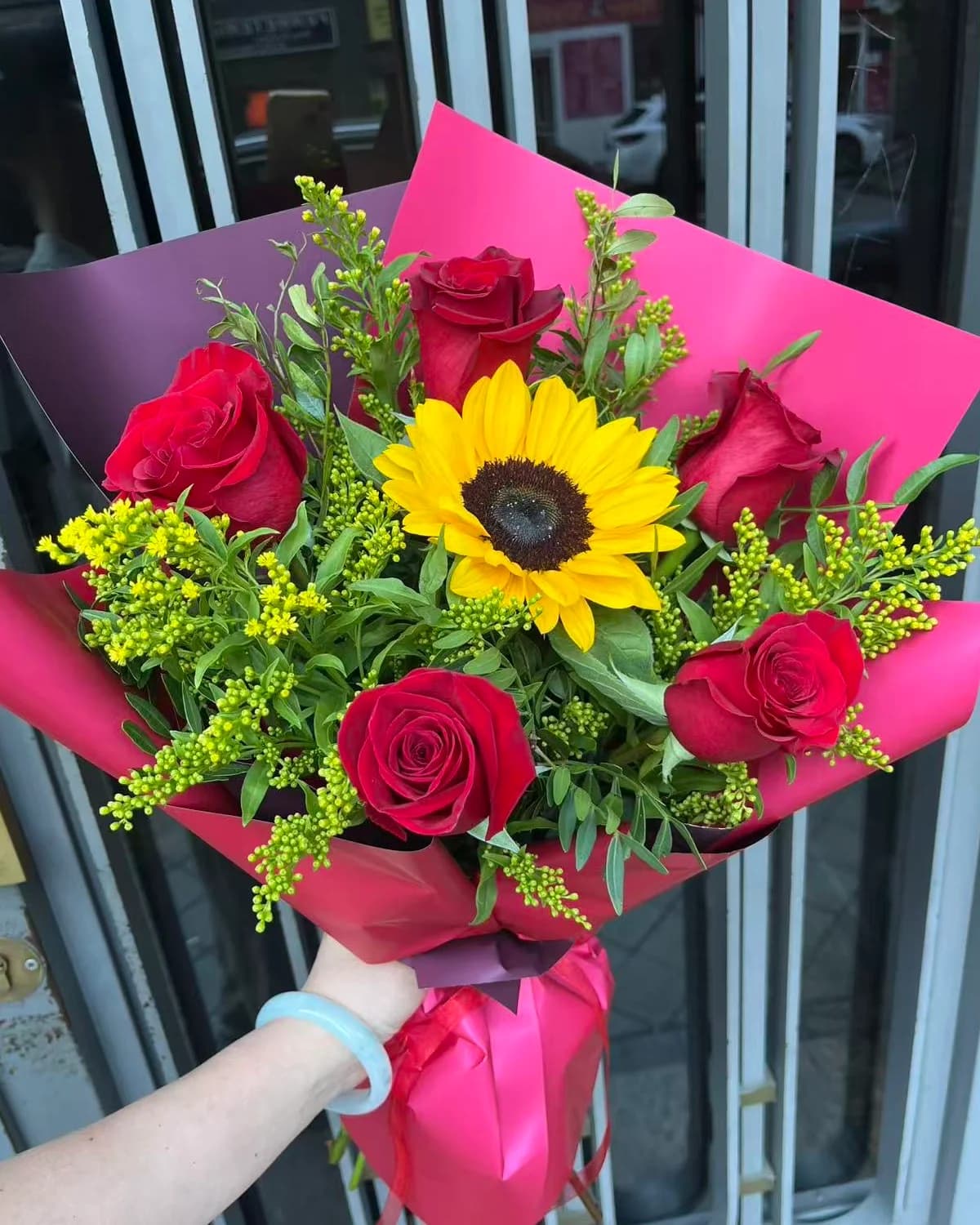 Ramo Destello de rosas rojas, girasol y solidago en papel fucsia