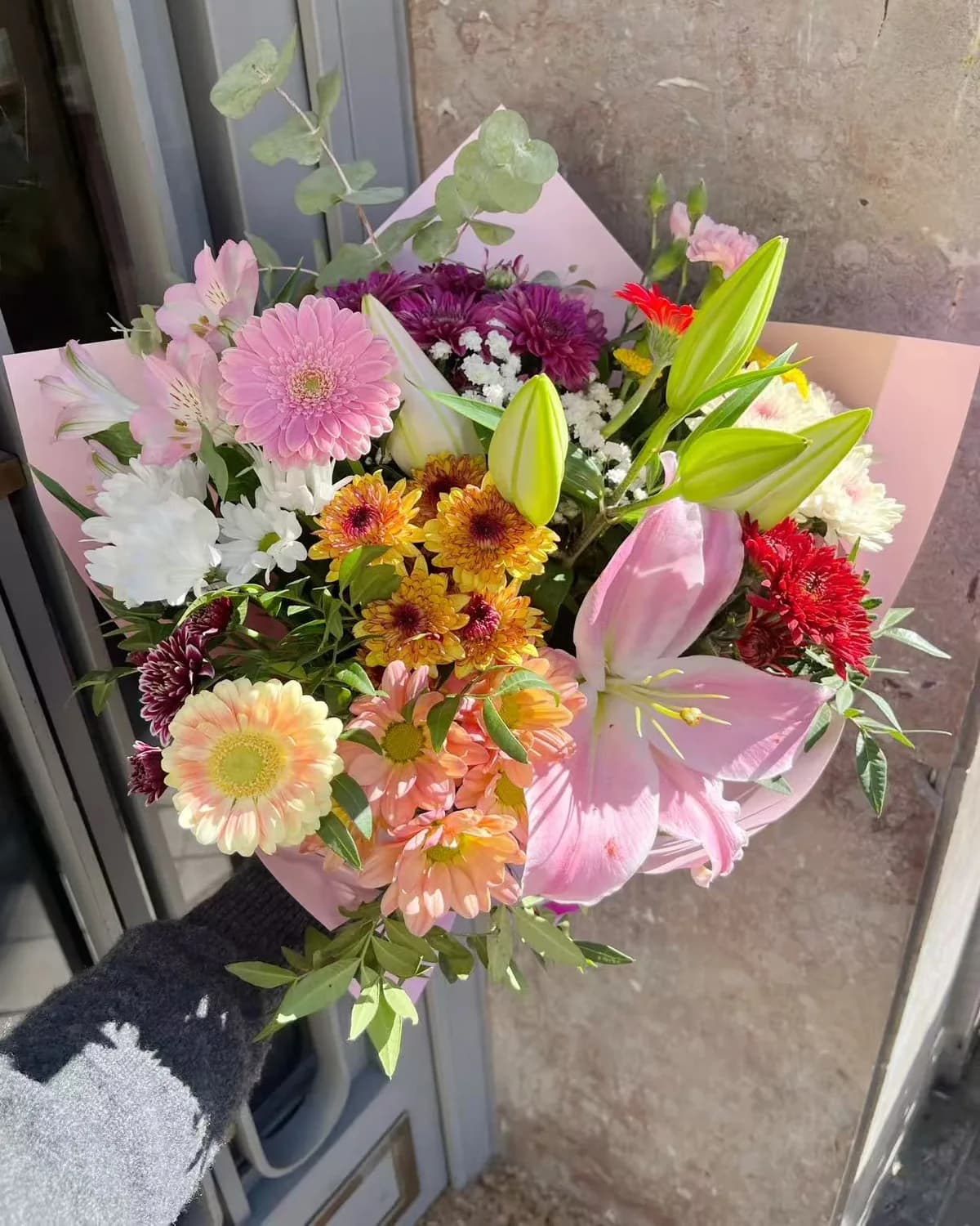 Ramo multicolor con lilium rosa, gerberas, crisantemos y alstroemerias en papel rosa