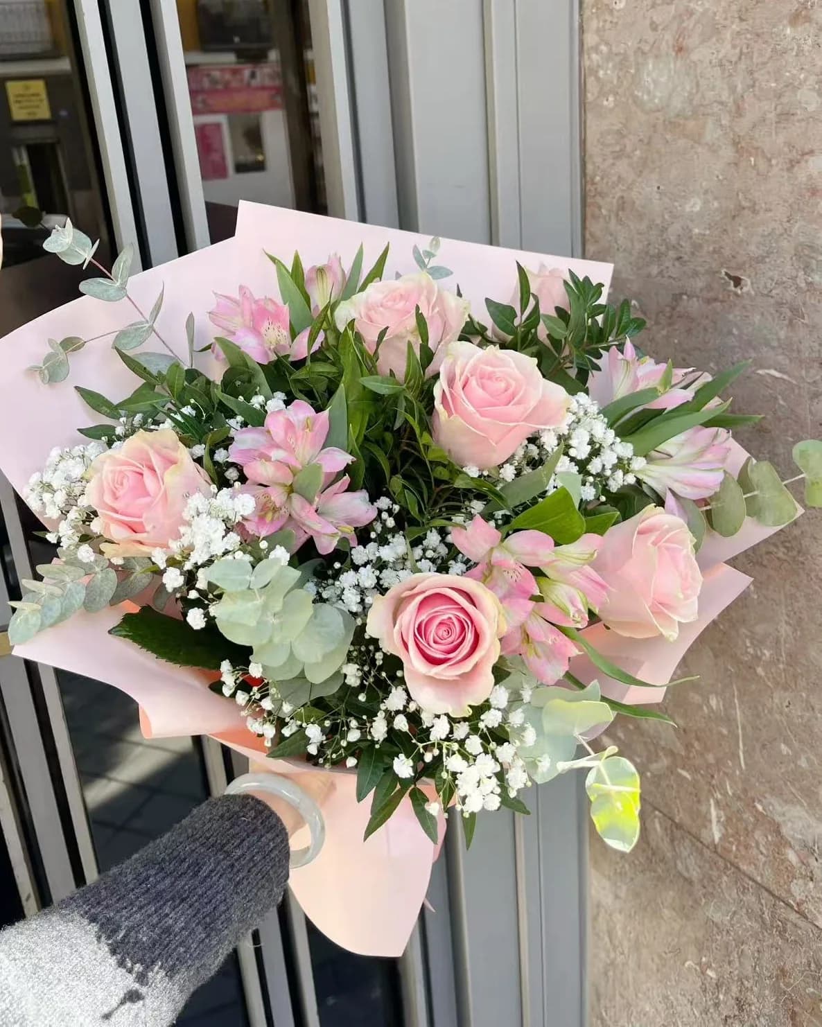 Ramo rosa de rosas rosa pálido y alstroemerias con paniculata y eucalipto en papel rosa empolvado